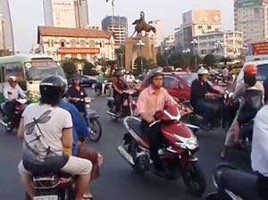 Walking across a busy roundabout in the centre of Ho Chi Minh City, Vietnam. Part 2